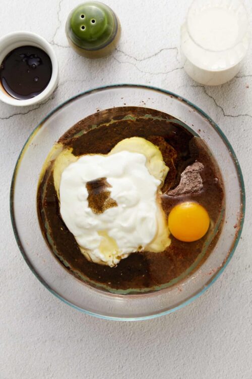Cream cheese, eggs, and seasonings in a mixing bowl for baking or cooking recipes.