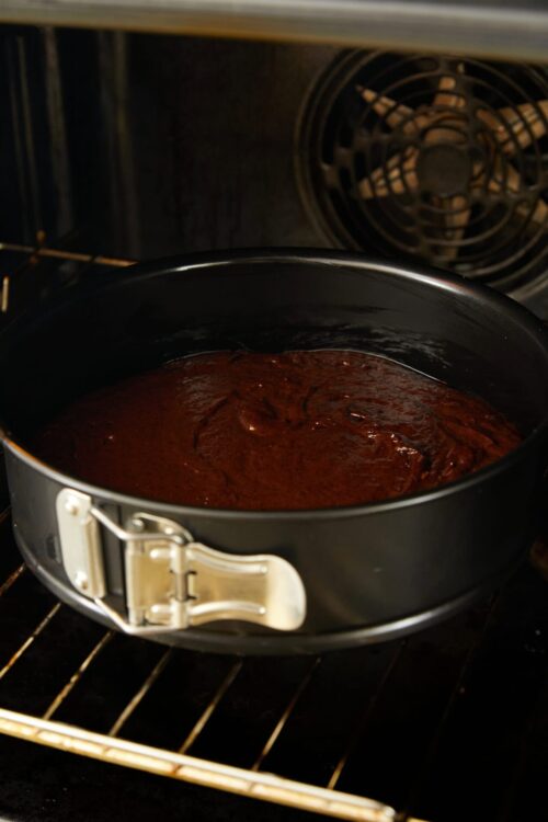 Rich chocolate cake batter in a springform pan baking in the oven.