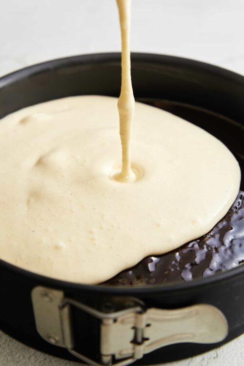 Soft caramel filling being poured into a chocolate tart shell.