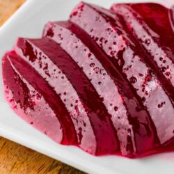 Fresh homemade raspberry gelatin dessert with a vibrant red color on a white plate.