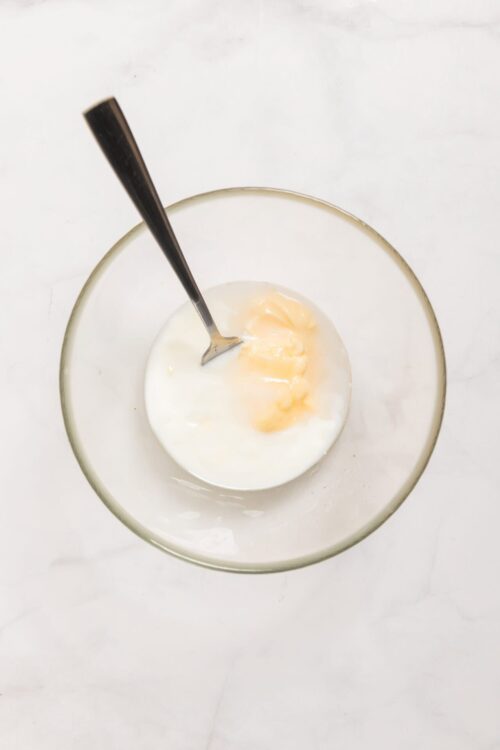 Cream mixture in a glass bowl with a spoon, ideal for baking recipes.