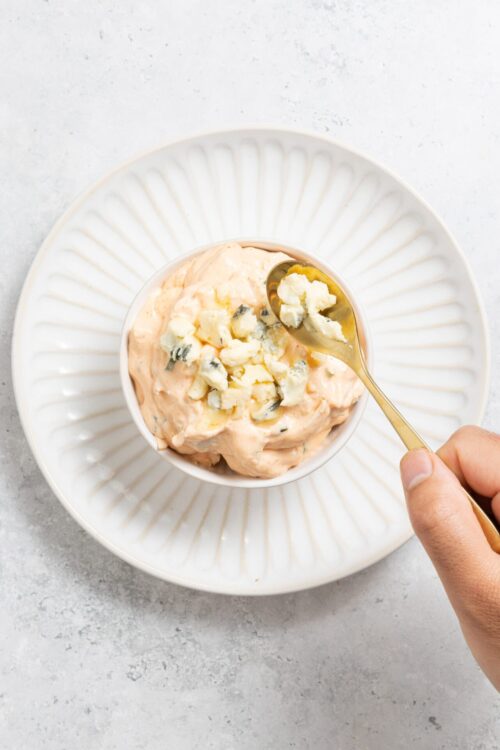 Creamy blue cheese dip in a small bowl, topped with crumbled blue cheese. Perfect appetizer or side dish for cheese lovers.