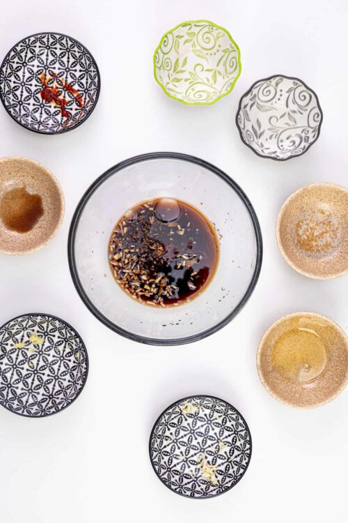 Soy sauce and seasoning bowls for cooking or dipping, arranged on a white surface.