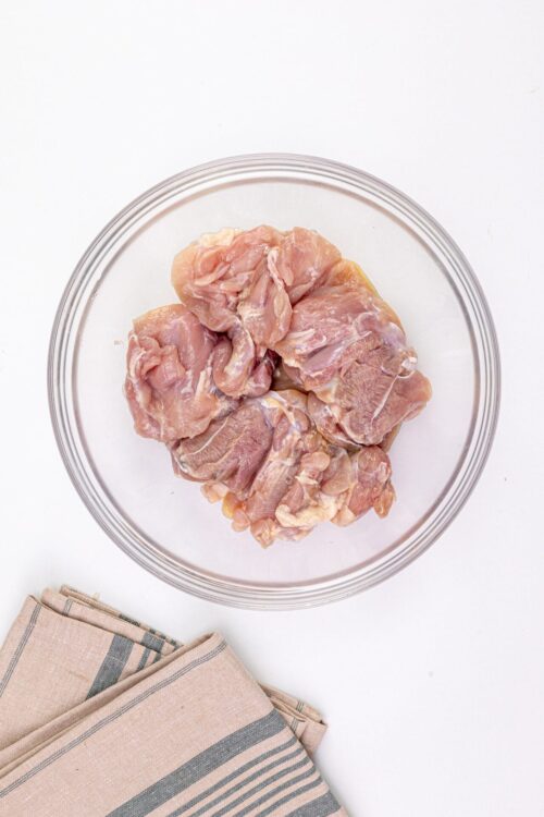Raw chicken thighs in a glass bowl for baking or cooking.