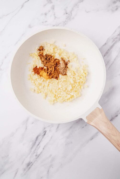 Cream cheese and spices in a white skillet for baking recipes.