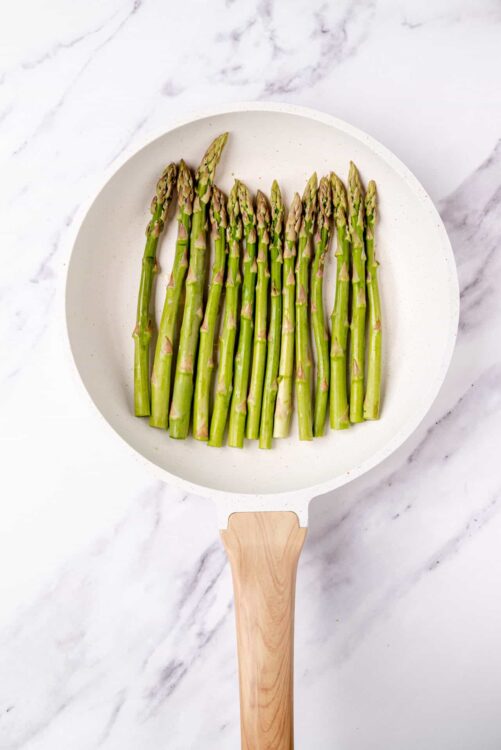Fresh roasted asparagus in a white skillet, ready to serve or cook.