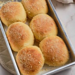 Buttery dinner rolls fresh from the oven on a baking sheet.