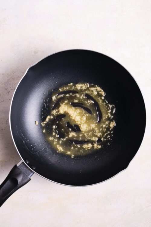 Minced garlic and butter in a black non-stick skillet, cooking for perfect flavor infusion.