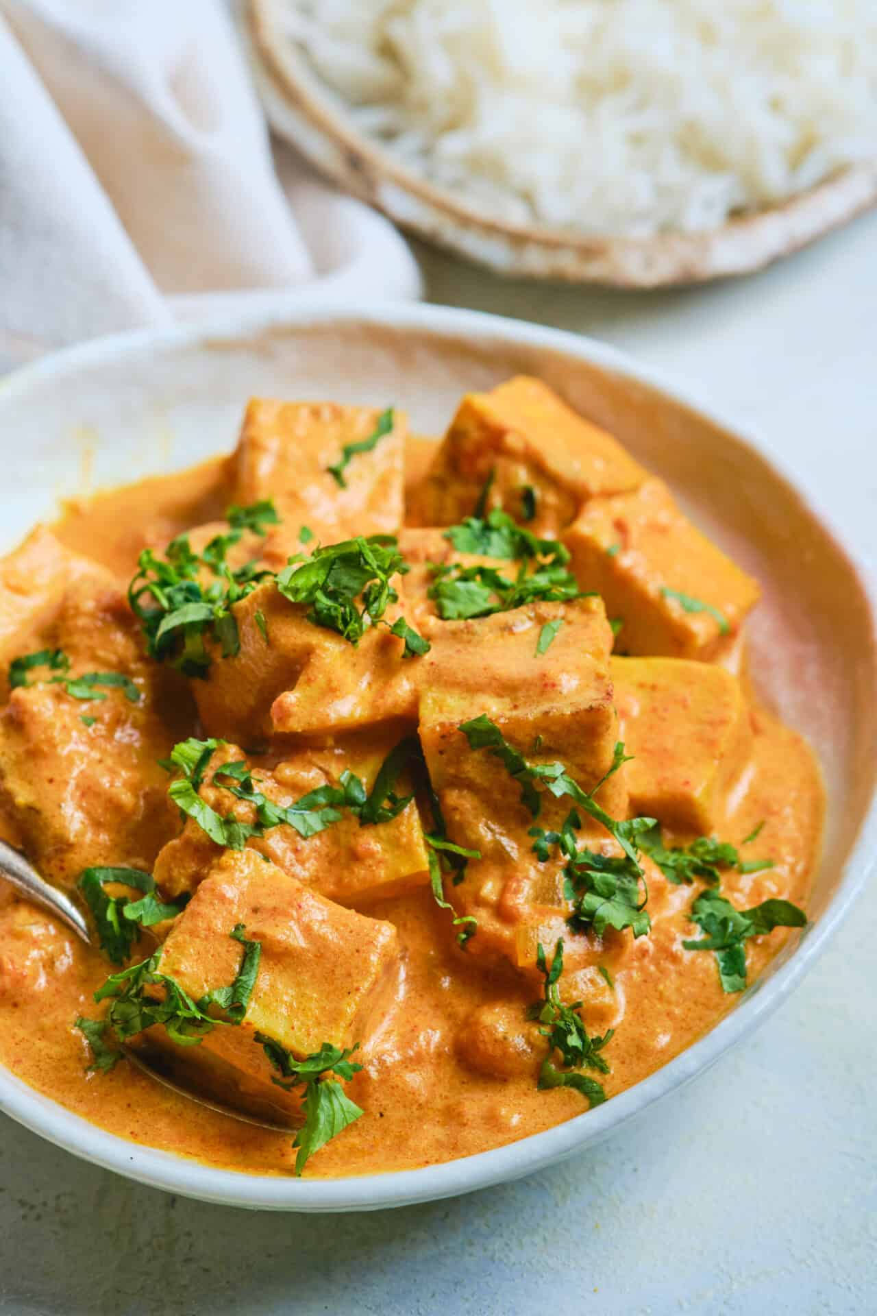 Creamy vegan curry with tofu and fresh herbs in a bowl.