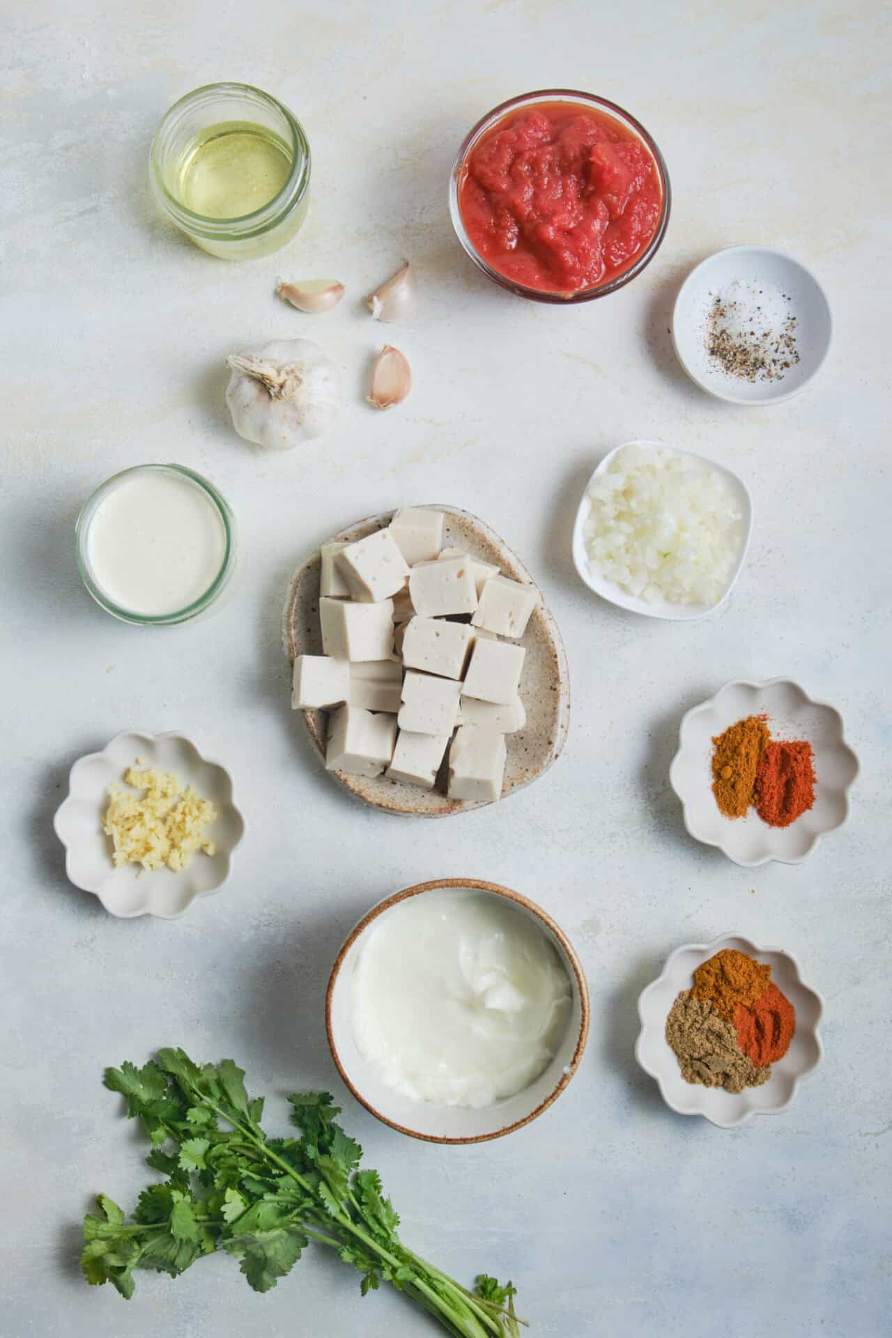 Buttermilk, garlic, and spices for queso dip with garlic, tomatoes, and herbs on a white background.