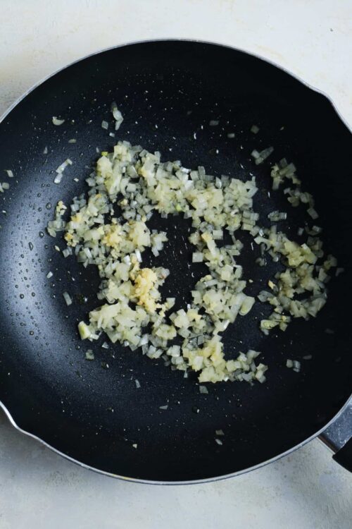 Sautéed chopped onions in a black skillet for cooking or recipe preparation.