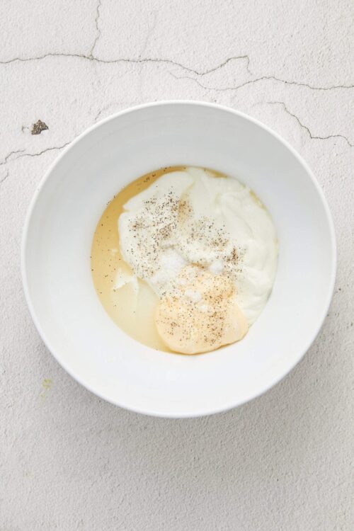 Creamy yogurt with vanilla bean and ground black pepper in a white bowl, ready for breakfast or dessert.