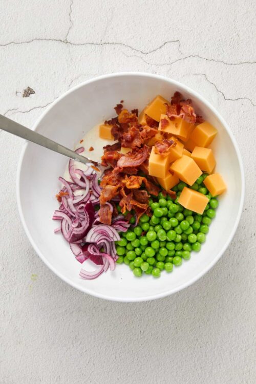 Crispy bacon, cheddar cheese, peas, red onion in a creamy salad bowl.