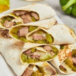 Fajita steak and green pepper quesadilla burritos on a white plate, close-up, delicious Mexican-inspired meal.