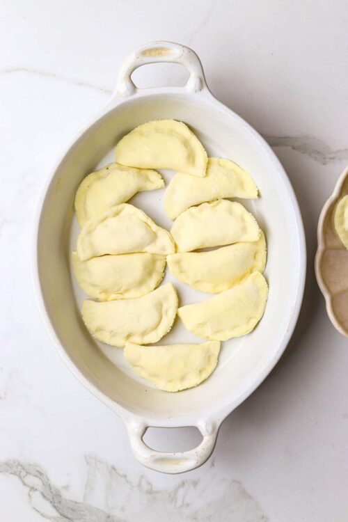 Sweet potato pierogi in a white baking dish ready for cooking or baking. Homemade savory potato dumplings for comfort food recipes.