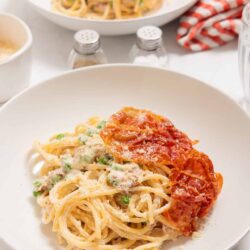 Creamy chicken Alfredo pasta with tomato marinara on white plate.