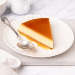 Rich caramel flan dessert on white plate, smooth and creamy, topped with shiny caramel sauce. Perfect for indulgent dessert recipes.