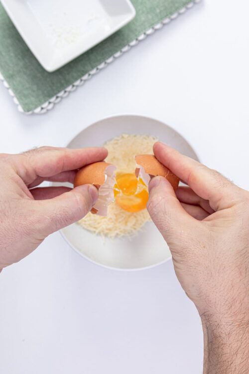 Cracked eggs in hands over baking ingredients, preparing for baking.