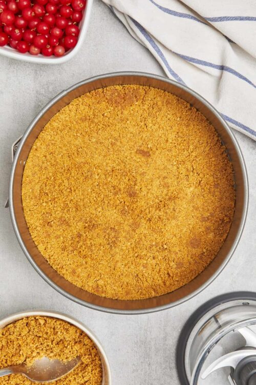 Golden graham cracker crust in a round baking pan for cheesecake or pie.
