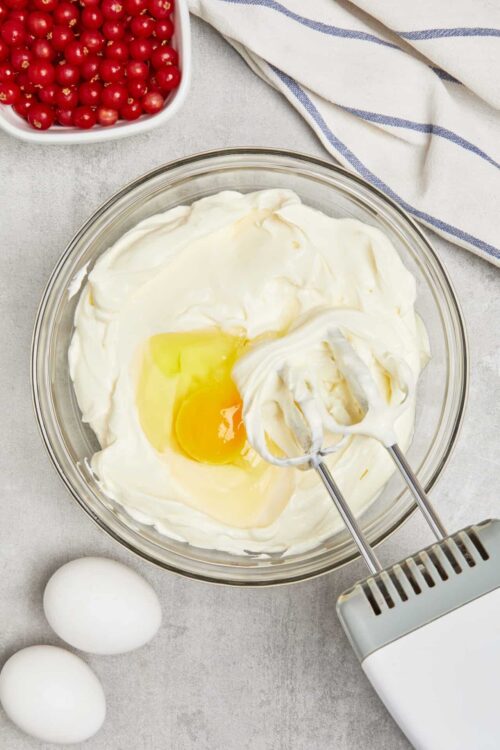 Cream cheese and eggs in a mixing bowl for baking recipe.