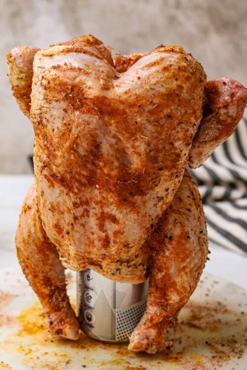Juicy roasted whole chicken with crispy seasoned skin on a can roasting stand.