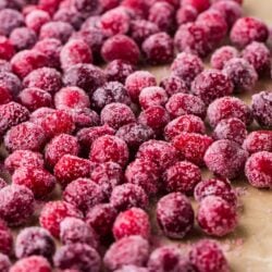 Frozen raspberries on parchment paper for baking or snacking.