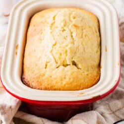 Fluffy homemade cornbread in a red ceramic baking dish.