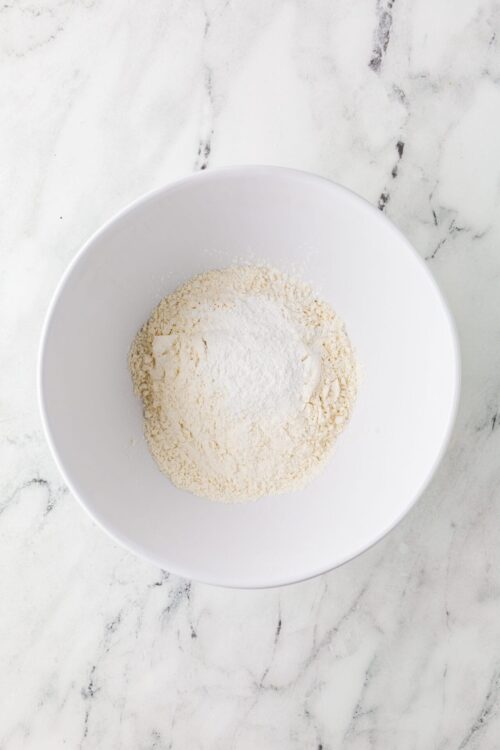 All-purpose flour and baking ingredients in a white mixing bowl for baking recipes.