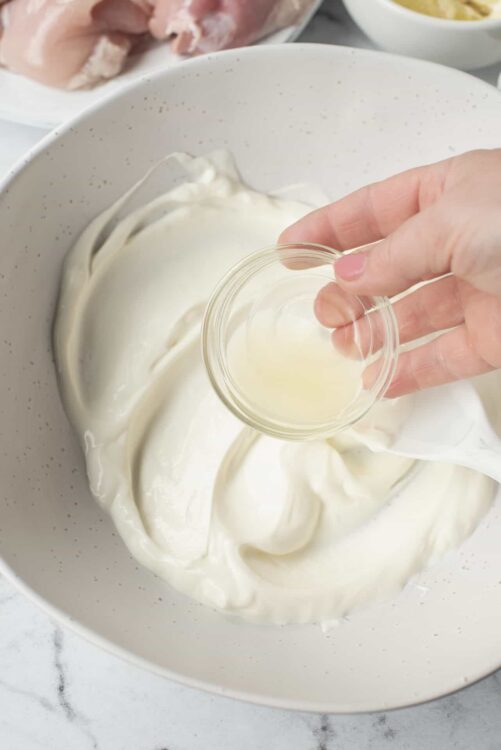 Smooth homemade mayonnaise being prepared with ingredients in a white bowl.