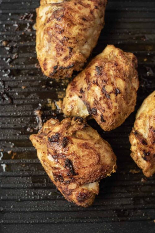 Juicy grilled chicken thighs with crispy, golden-brown crust on a black grill grate. Perfect for summer barbecues and family dinners.