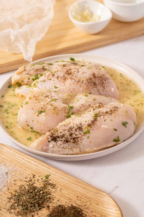 Juicy baked chicken breasts in creamy herb marinade with spices and fresh herbs.