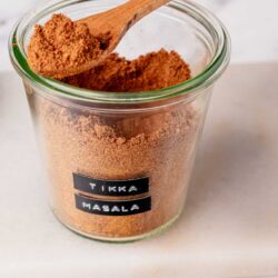 Ground spices, Tikka Masala in a glass jar with a wooden spoon, Indian spice blend for cooking.