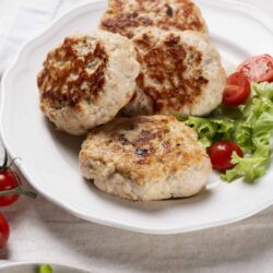Juicy homemade chicken meatballs served with fresh salad on a white plate.