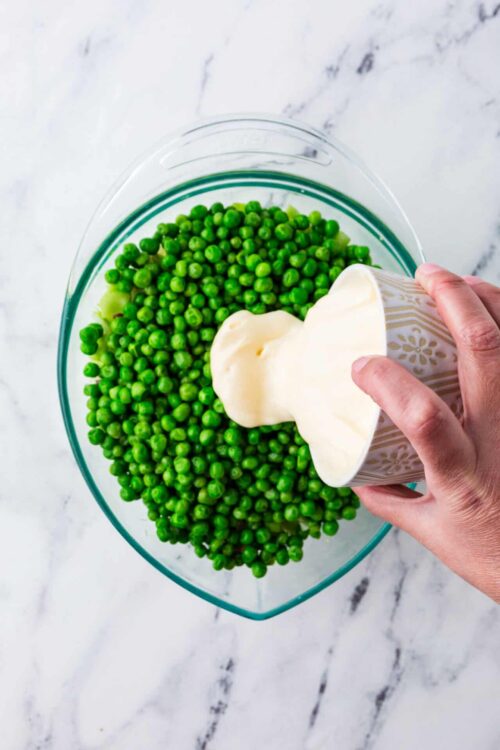 Fresh green peas and creamy butter in a glass bowl, ready for cooking or recipe preparation.