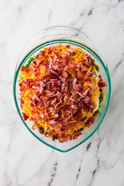 Baked Bree bacon cheesy potato casserole with green onions in a glass baking dish.