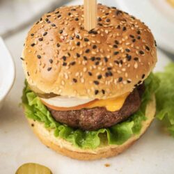 Juicy cheeseburger with lettuce, tomato, and pickles on a toasted sesame bun.
