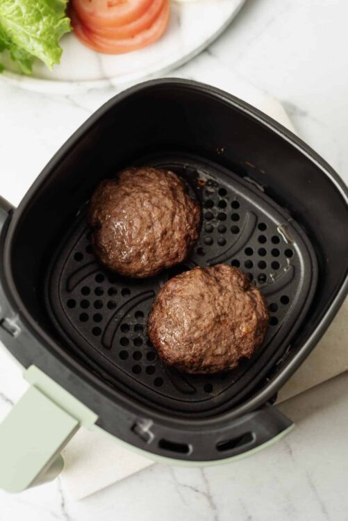 Juicy beef meatballs cooking in an air fryer basket, ready for a flavorful meal.