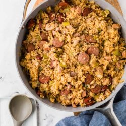 Savory chicken and sausage fried rice in a skillet with vegetables and seasonings.