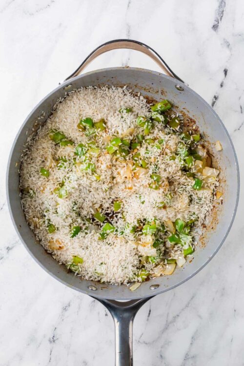 Rice and green onion cooking in a skillet.