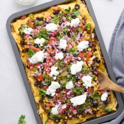 Crispy baked taco casserole with fresh vegetables and sour cream.