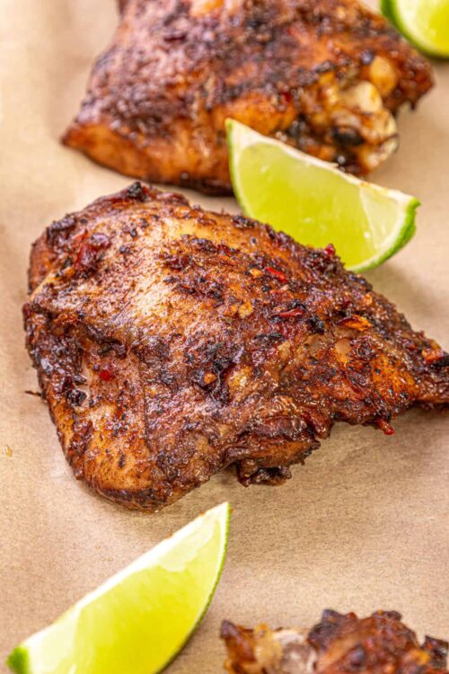 Succulent smoked chicken quarter with rich marinade and lime wedges.