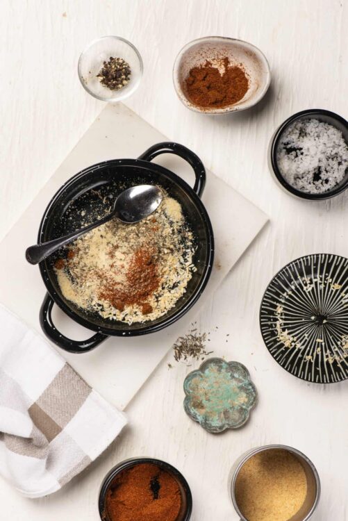Ground spices and herbs in bowls, ready for baking or cooking process, on a white kitchen countertop.