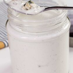 Creamy blue cheese dressing in a glass jar with a spoon.