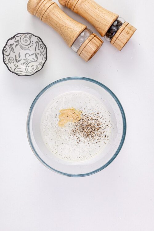 Ground black pepper and salt in a glass bowl for seasoning recipes.