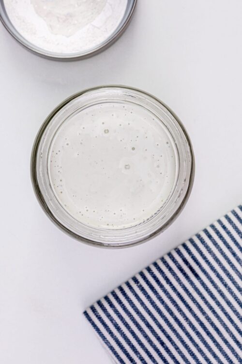 Creamy homemade bread dough in a glass mixing bowl for baking.