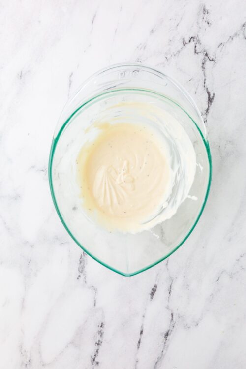 Creamy vanilla frosting mixed in a glass bowl.