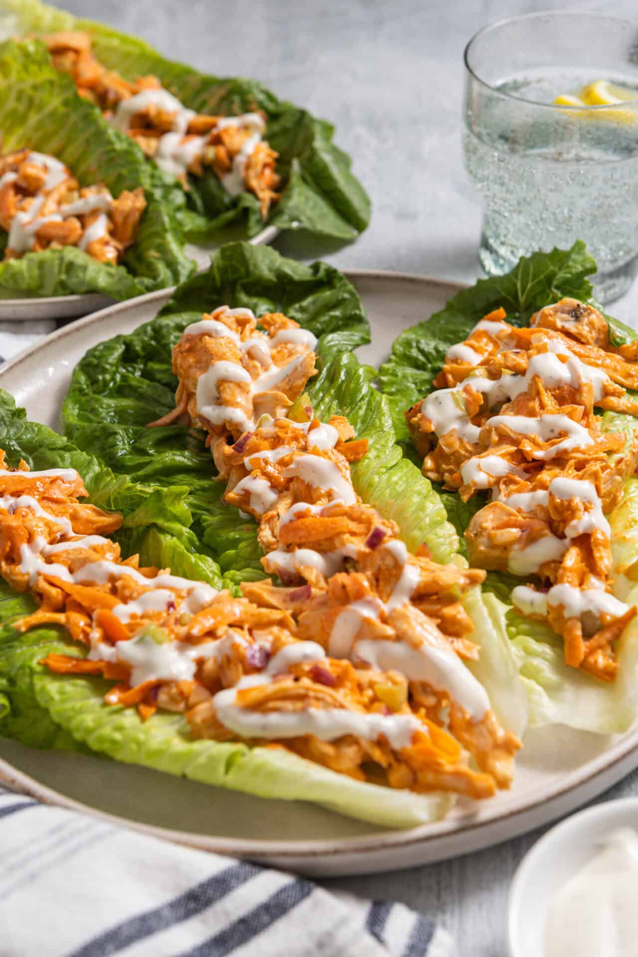 Baked buffalo chicken lettuce wraps with creamy dressing, served on fresh romaine leaves.