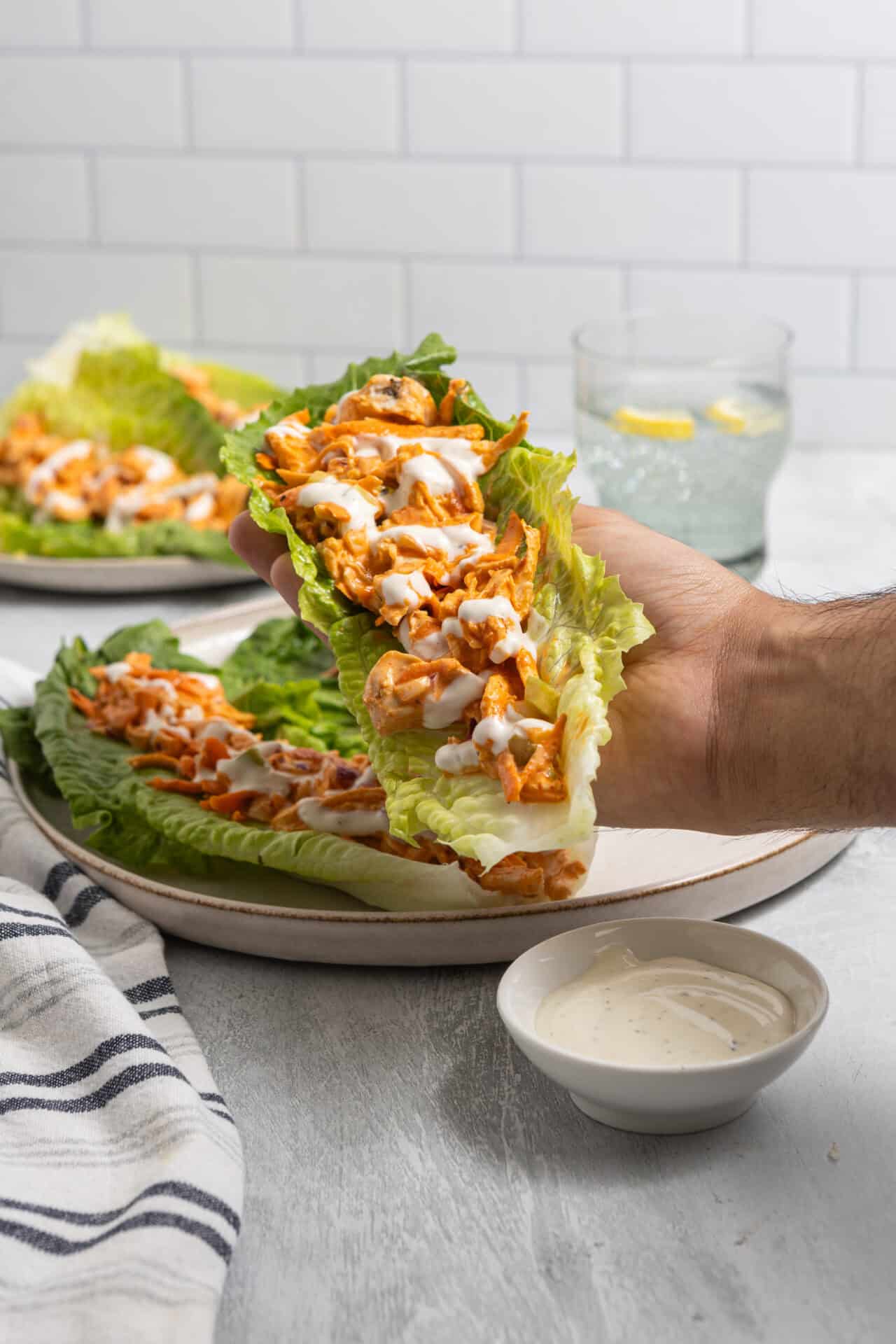 Savory shredded chicken lettuce wraps with creamy sauce on a rustic plate.