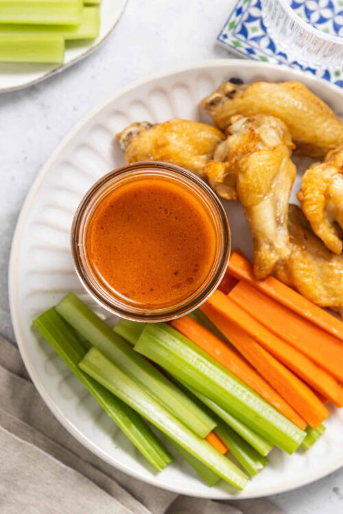 Buttermilk chicken wings with celery, carrots, and buffalo sauce, healthy baked appetizer, easy recipe for game day.