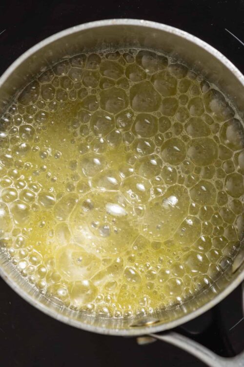 Golden melted butter sizzling in a saucepan, perfect for baking and cooking recipes.